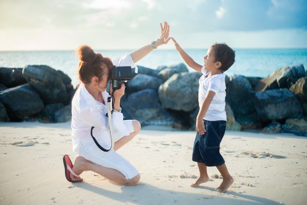 A Paradise Photography photographer high-fiving a child during a beach session