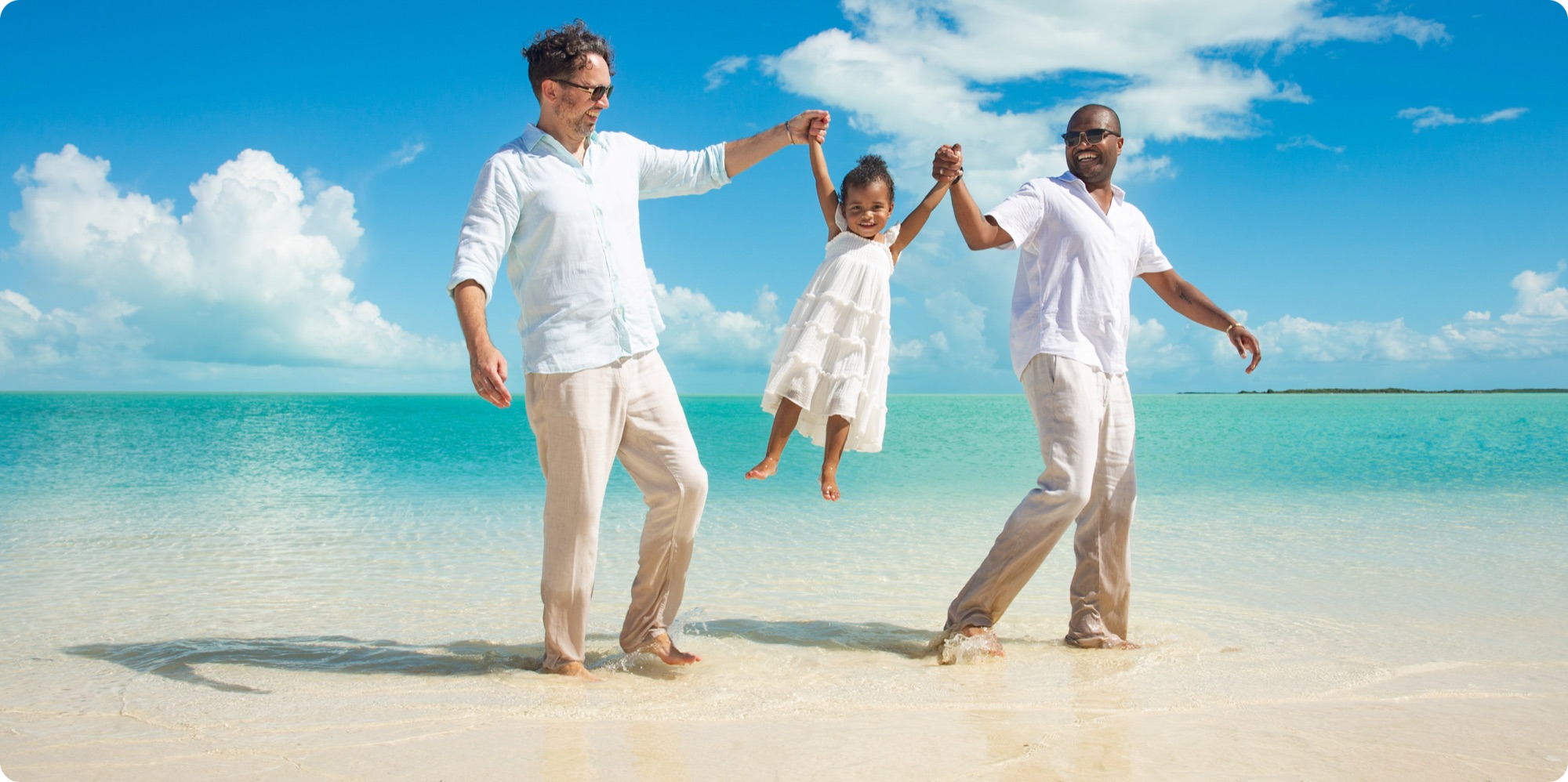 Parents swinging their daughter on the beach in Turks and Caicos
